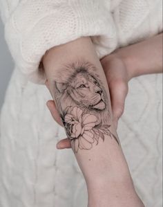 a woman's arm with a lion and flower tattoo on the left side of her arm