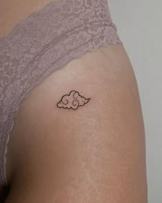 a small cloud tattoo on the back of a woman's thigh