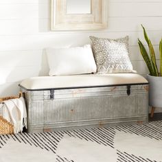 a metal box sitting on top of a white floor next to a potted plant