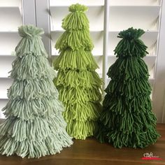 three green and white christmas trees sitting on top of a wooden table