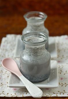 there are two glass jars on the table with spoons