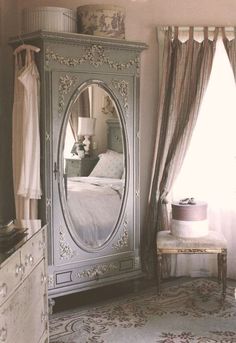 a bedroom scene with focus on the armoire and bed in the background, along with a large window