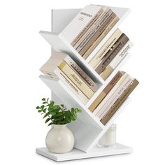 a white book shelf holding books and a vase with a plant in it on a white surface