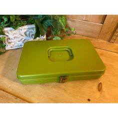 a green suitcase sitting on top of a wooden table