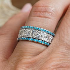 a woman's hand with two rings on it and blue stones in the middle