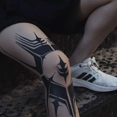 a person sitting on a bench with their legs covered in black and white tattoo designs