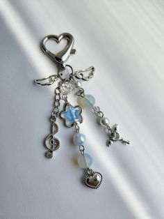 a keychain with charms attached to it on a white tablecloth, in the shape of a heart