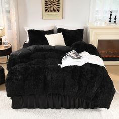 a bed with black comforter and pillows in a room next to a fire place