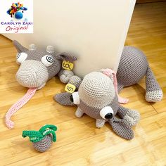 two crocheted stuffed animals sitting next to each other on a wooden floor near a wall