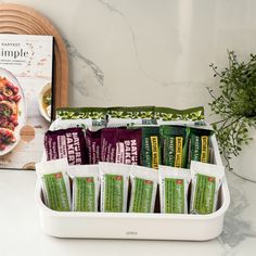 an open lunch box with some snacks in it and a cookbook next to it