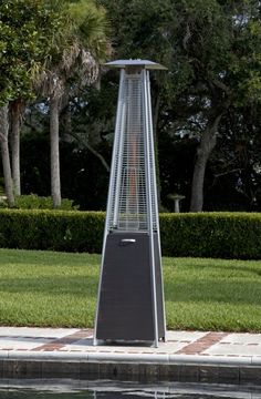 an outdoor heater sitting on the side of a pool in front of some trees