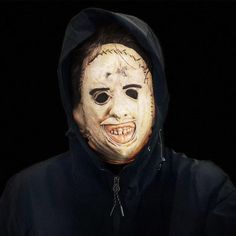 a man wearing a creepy mask with writing on it's face and hoodie