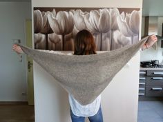 a woman holding up a shawl in front of a painting