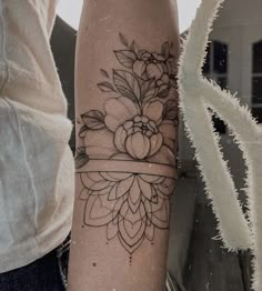 a woman's arm with a flower and ribbon tattoo on the left inner forearm