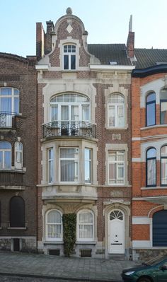 an apartment building with many windows and balconies on the front, along with a car parked in front