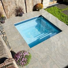 an empty swimming pool in the middle of a backyard with stone walls and landscaping around it