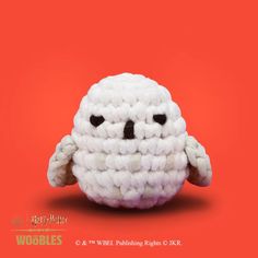 a crocheted white stuffed animal with black eyes on an orange and red background