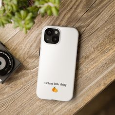 a white phone case sitting on top of a wooden table next to a black camera