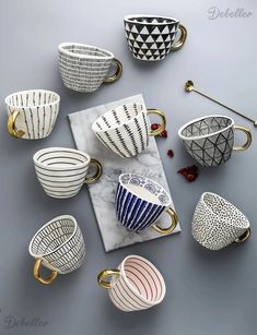 coffee cups and saucers on a marble table with gold handles in various shapes, sizes and colors