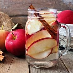 an apple cider with cinnamon sticks and apples in the background on a wooden table