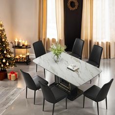 a dining room table with black chairs and a christmas tree in the corner behind it