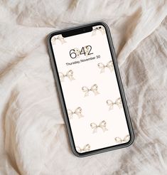 an iphone case sitting on top of a bed covered in white sheets with bows and numbers