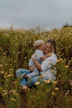 a woman holding a baby in a field of flowers