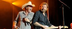 two men on stage with guitars and microphones