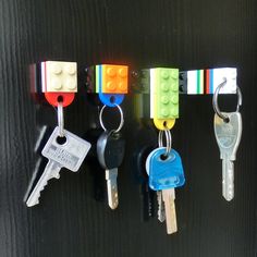 four lego key chains hanging on a black wall