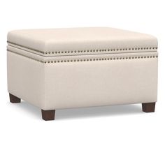 a white ottoman with studded trimmings on it