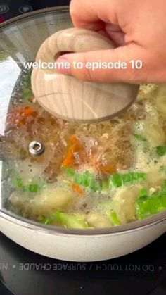 someone is stirring vegetables in a pot with a wooden spoon to stir them into broth