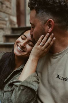 a man and woman cuddle close to each other as they smile at the camera