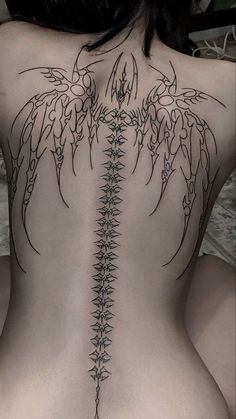 the back of a woman's body with an intricate tattoo design on her ribs