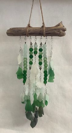 a wind chime hanging from a tree branch with green and white beads on it