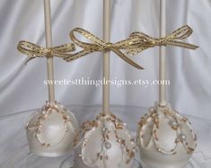 three white cake pops with gold bows on them