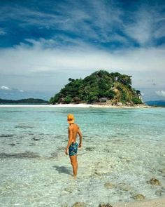 a man standing in shallow water near an island