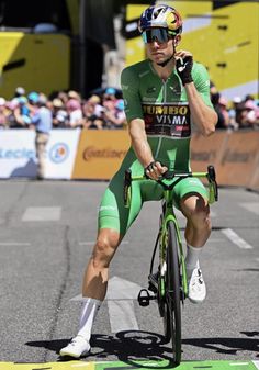 a man riding a bike while talking on a cell phone in front of a crowd