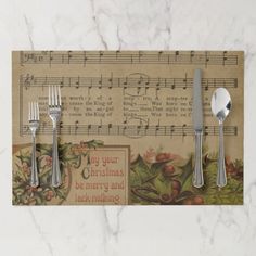 a place mat with spoons, fork and knife on it that has sheet music in the background