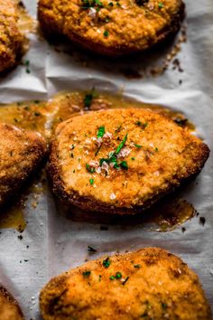 some fried meat patties are on a piece of parchment paper with parsley sprinkled on top