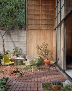 an outdoor patio with chairs, table and potted plants on the side of it