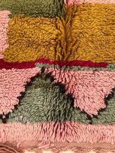 a pink, green and yellow rug with fringes on it's edges is shown