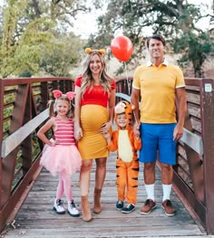 a family dressed up as winnie the pooh and tigger on a bridge with balloons