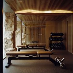 an indoor gym with benches, dumbs and exercise equipment on the floor in front of a stone wall