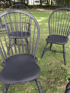 three chairs sitting in the grass near each other