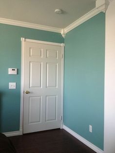 an empty room with a white door and blue walls