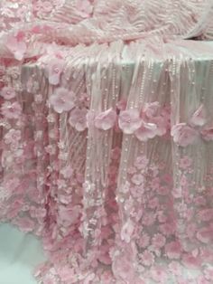 pink flowers are on the table cloths and is being made from sheer fabric with sequins