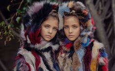 two mannequins dressed in colorful fur coats with hoods over their heads