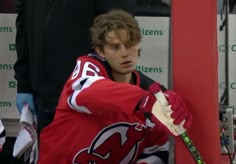 a young man in red jersey holding a hockey stick