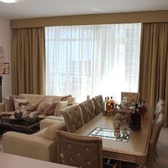 a living room filled with furniture next to a window covered in curtains and drapes