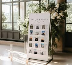 a white sign sitting on top of a table next to candles and vases filled with flowers